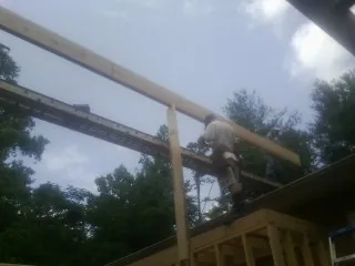 Carpenter setting a ridge beam over a new addition frame — Ice Dam Removal by Roofing Brothers in Forestdale