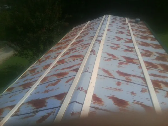 Rusted metal roof panels with new wood purlins before replacement — Storm Damage Roof Repair in Forestdale by Roofing Brothers