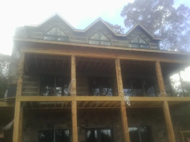 Dormers and porch framing on a large log home under construction — Roof Coating work by our crew in Forestdale