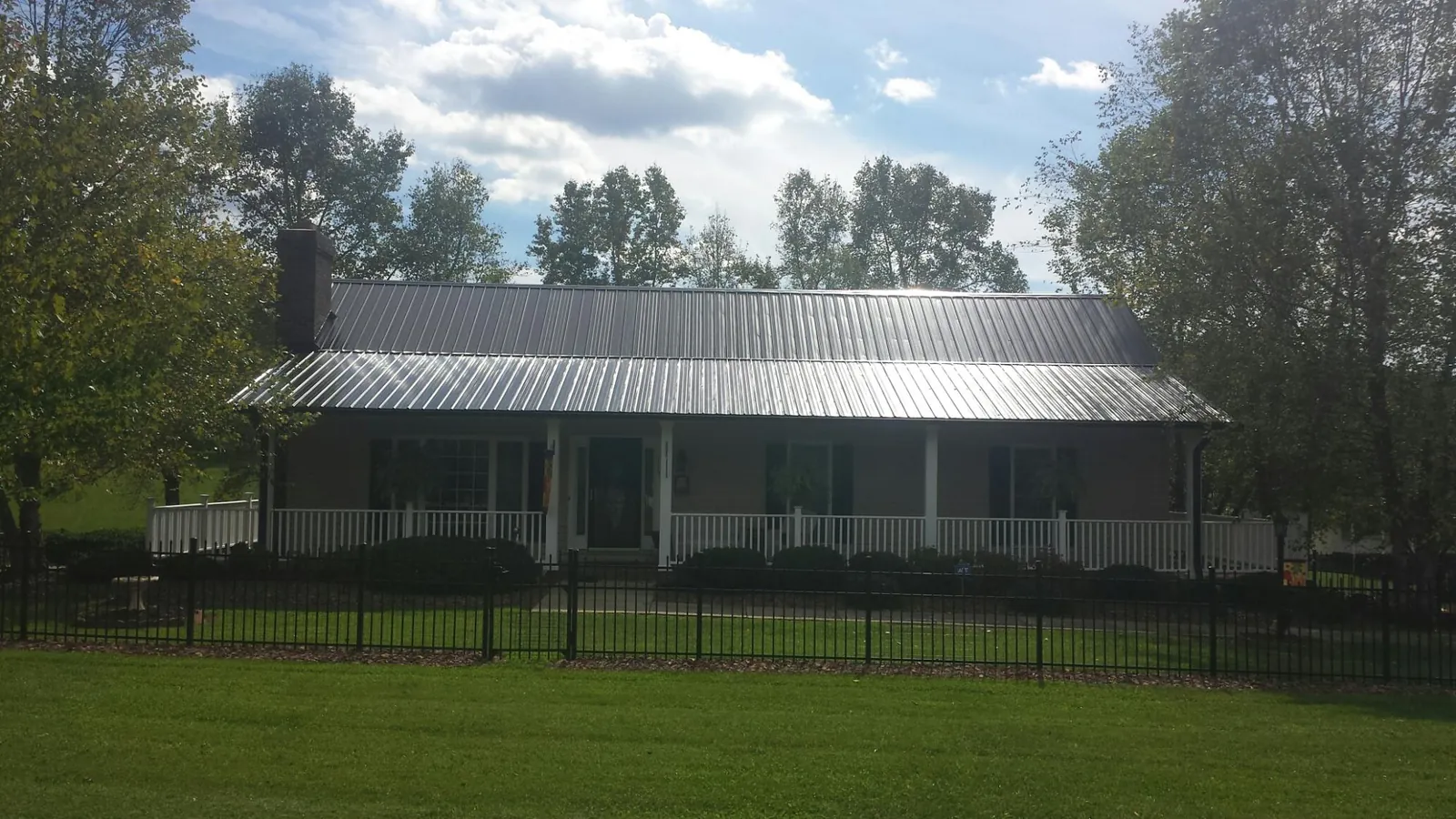 Gray metal roof on a brick ranch with a full width front porch — Gutter Guard Installation work by our crew in Forestdale