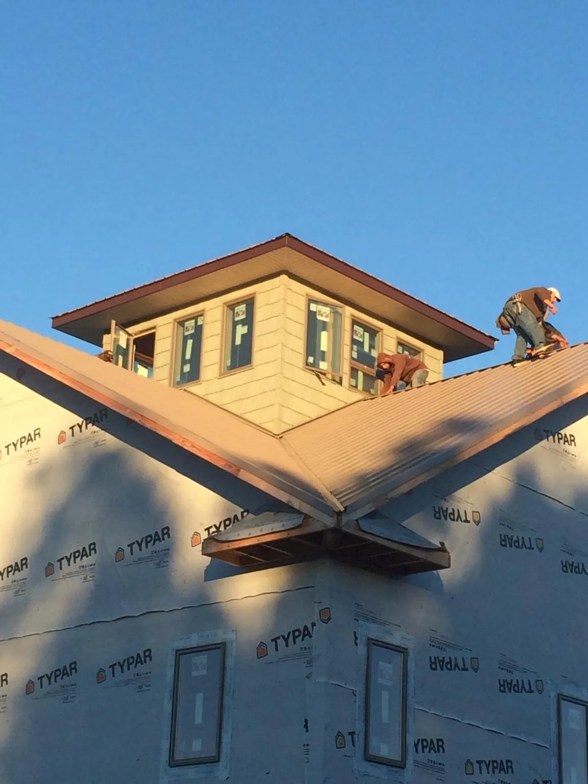 Roofers working around a rooftop cupola on a new metal roof at sunset — Roof Waterproofing in Forestdale by Roofing Brothers